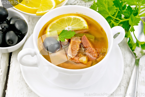 Image of Solyanka with lemon in white bowl on board