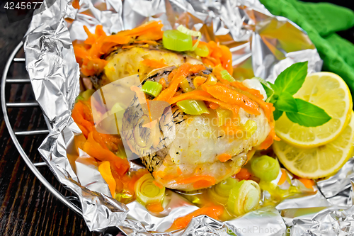 Image of Pike with carrots and basil in foil on dark board