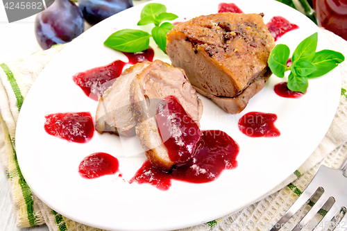 Image of Duck breast with plum sauce in plate on board