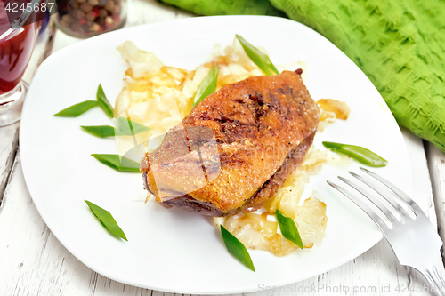 Image of Duck breast with cabbage and onions in plate on board