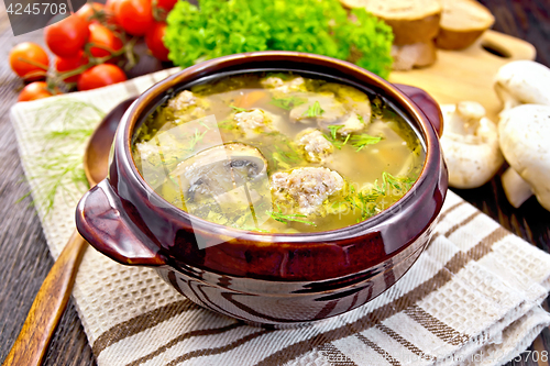 Image of Soup with meatballs and mushrooms in brown bowl on dark board