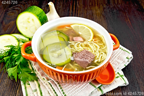 Image of Soup with zucchini and noodles in bowl on kitchen towel