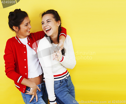 Image of lifestyle people concept: two pretty young school teenage girls having fun happy smiling on yellow background 