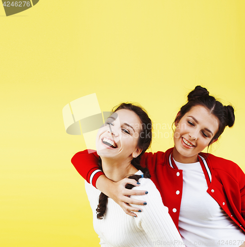 Image of lifestyle people concept: two pretty young school teenage girls having fun happy smiling on yellow background 