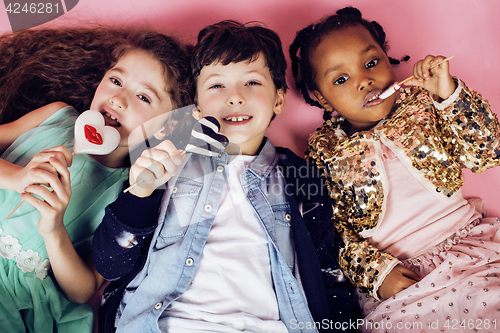 Image of lifestyle people concept: diverse nation children playing together, caucasian boy with african little girl holding candy happy smiling closeup