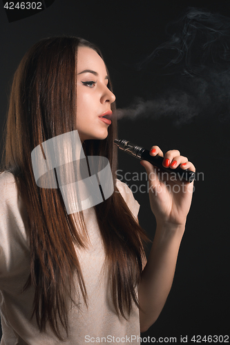 Image of The face of vaping young woman at black studio