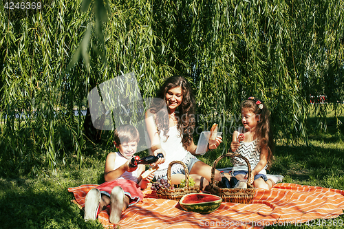 Image of cute happy family on picnic laying on green grass mother and kid