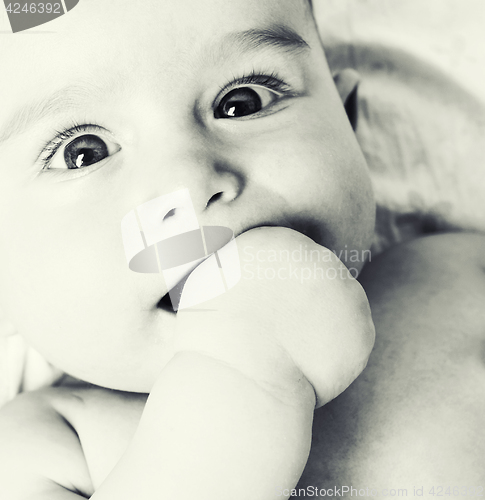 Image of little sweet baby close up, hand in mouth smart looking