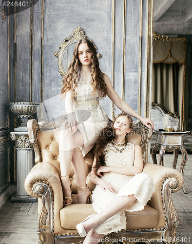 Image of two pretty twin sister blond curly hairstyle girl in luxury house interior together, rich young people concept 