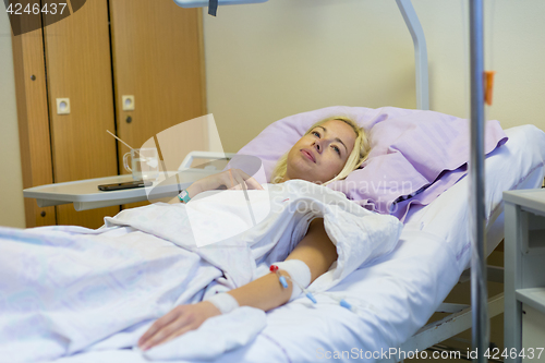 Image of Bedridden female patient recovering after surgery in hospital care.