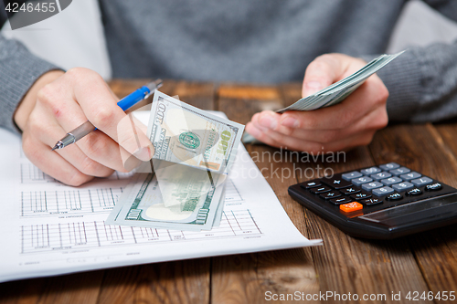 Image of Caucasian hands counting dollar banknotes on dark wooden table