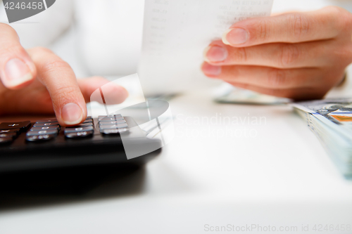 Image of savings, finances, economy and home concept - close up of hands with calculator counting money and making notes at home