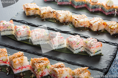 Image of set of sushi on a slate square plate. 