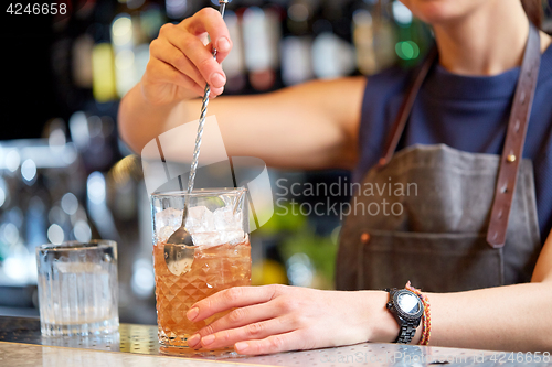 Image of bartender with cocktail stirrer and glass at bar