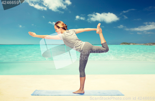 Image of woman making yoga in lord of the dance pose on mat