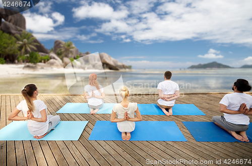 Image of group of people making yoga exercises outdoors