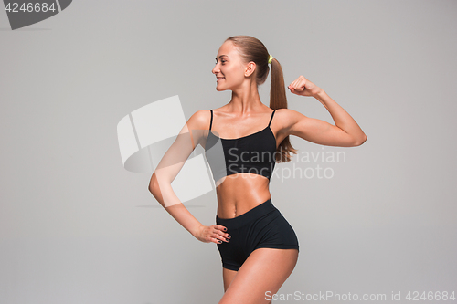 Image of Muscular young woman athlete on gray