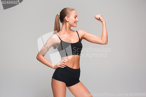 Image of Muscular young woman athlete on gray
