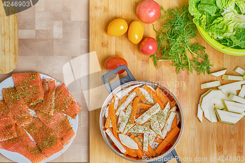 Image of Salmon fish preparation for cooking, chopped vegetables, salt and knife