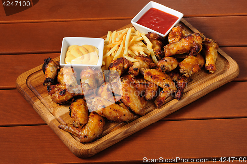 Image of Big wooden board with grilled chicken winds