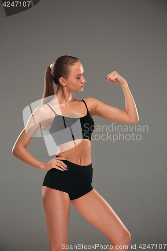 Image of Muscular young woman athlete on gray