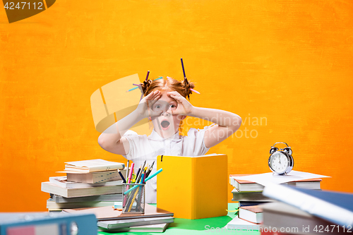 Image of The Redhead teen girl with lot of books at home. Studio shot