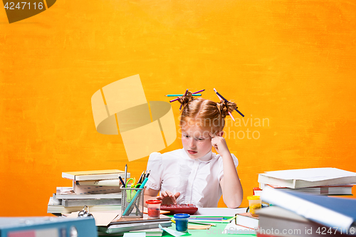 Image of The Redhead teen girl with lot of books at home. Studio shot