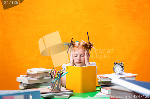 Image of The Redhead teen girl with lot of books at home. Studio shot