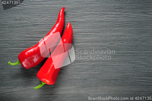 Image of Two red Kapia peppers on a dark shale stone background