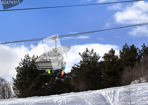 Image of Skiers and snowboarders on chair-lift in winter mountain