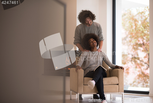 Image of multiethnic couple hugging in front of fireplace