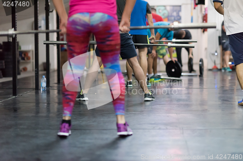 Image of a group of people exercise with an empty bar