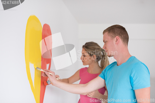 Image of couple are painting a heart on the wall