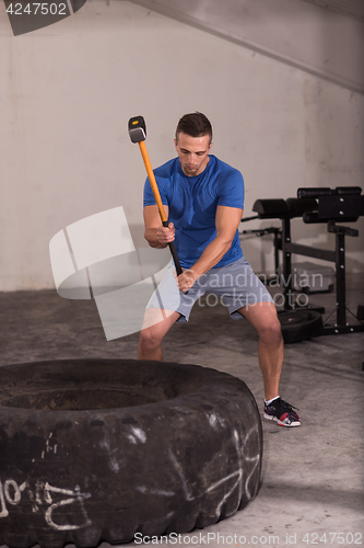 Image of man workout with hammer and tractor tire