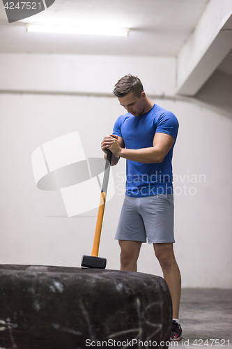 Image of man workout with hammer and tractor tire