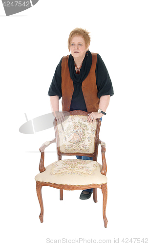 Image of Senior woman standing on armchair.