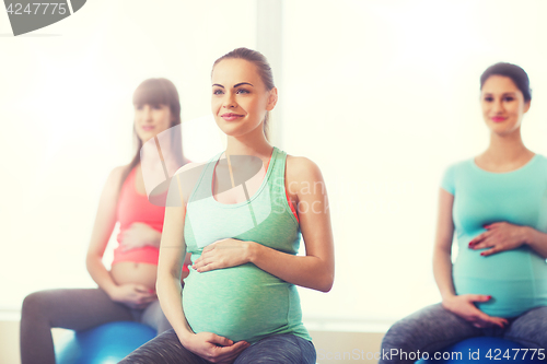 Image of happy pregnant women exercising on fitball in gym