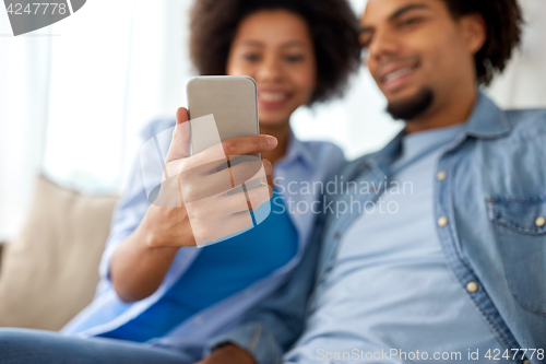 Image of happy couple with smartphones at home
