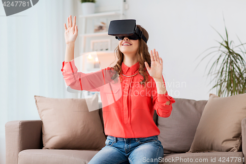 Image of happy woman in virtual reality headset at home