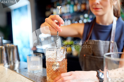 Image of bartender with cocktail stirrer and glass at bar