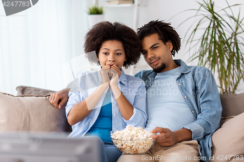Image of happy couple with popcorn watching tv at home