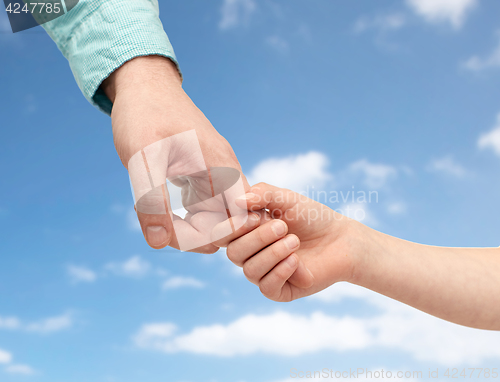 Image of father and child holding hands over blue sky