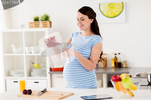 Image of pregnant woman with blender cup and glass at home