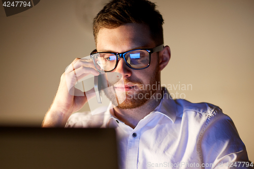 Image of businessman calling on smartphone at night office