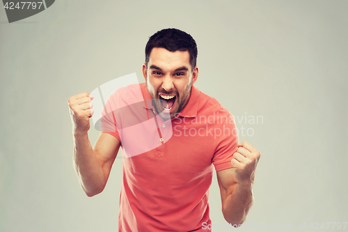 Image of happy man celebrating victory over gray background