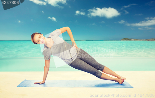 Image of woman making yoga in side plank pose on mat