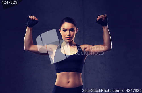 Image of young woman flexing muscles in gym