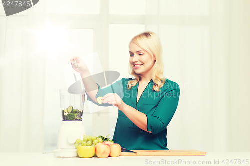 Image of smiling woman with blender cooking food at home