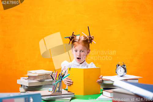 Image of The Redhead teen girl with lot of books at home. Studio shot