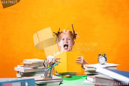 Image of The Redhead teen girl with lot of books at home. Studio shot